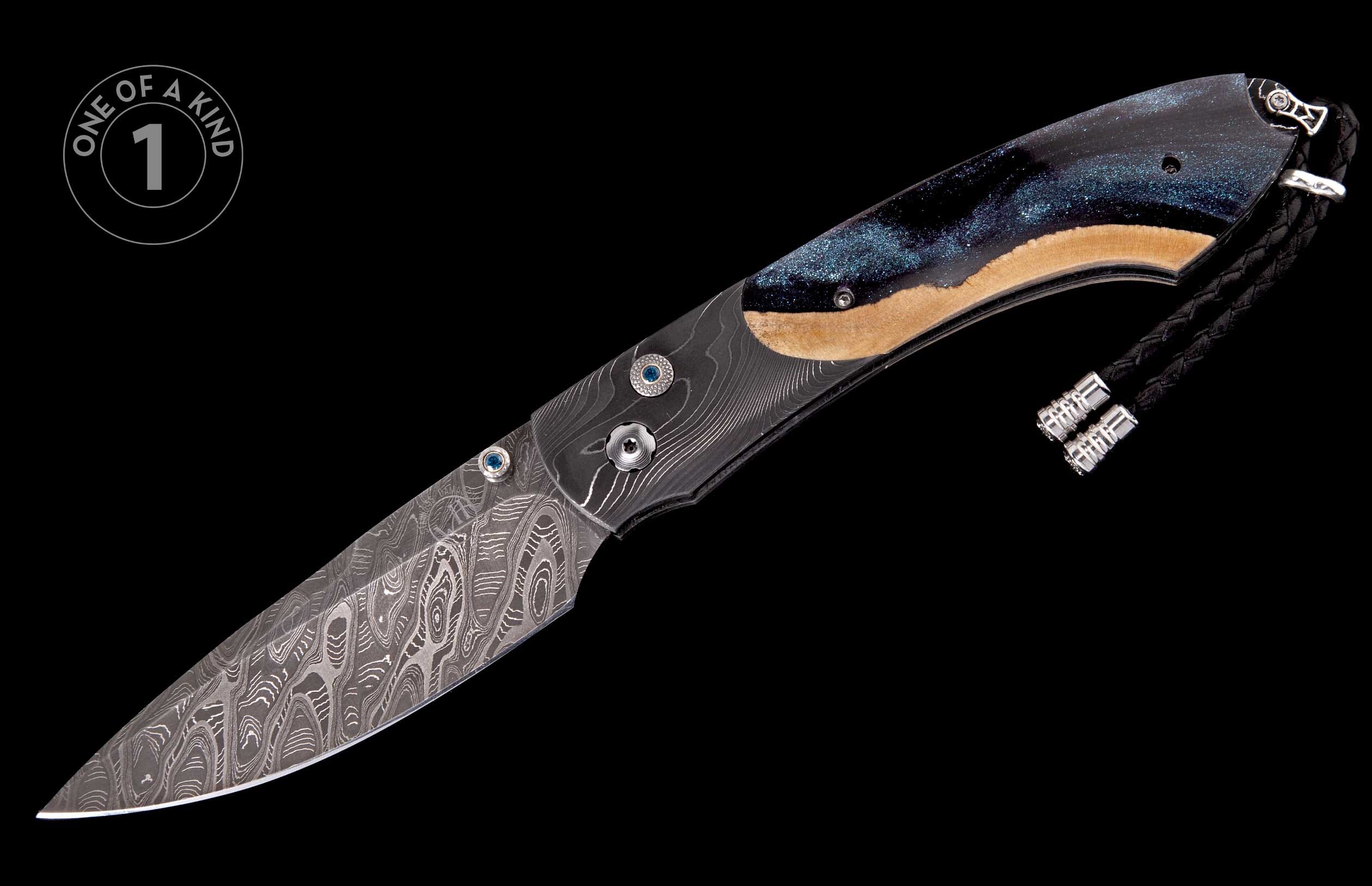 Damascus steel folding knife with a blue glitter and wood handle, featuring blue gemstone accents and a braided lanyard.