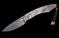 Engraved silver-toned folding knife with Damascus blade, featuring an oil derrick, American flag, scrollwork, and a black leather lanyard.
