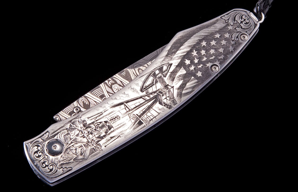 Metallic engraved knife with an American flag, oil rig, oil field workers, and ornate scrollwork.