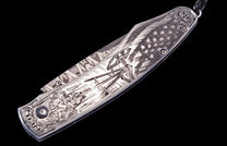 Metallic engraved knife with an American flag, oil rig, oil field workers, and ornate scrollwork.