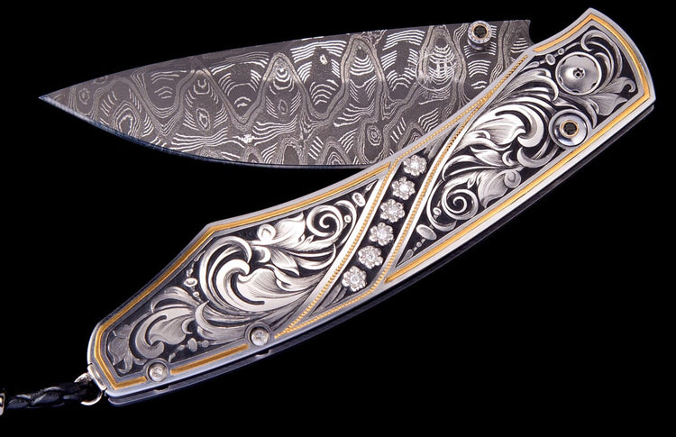 Ornate custom knife with a damascus steel blade, silver scrollwork engraving, gold accents, and five diamond flower clusters.