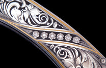 Decorative knife with intricate silver and gold scrollwork and six diamond-studded floral embellishments.
