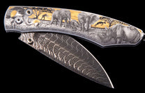 Engraved folding knife with a detailed safari scene handle featuring elephants, rhino, and hunter, displaying a patterned Damascus blade.