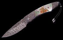 Samurai-themed folding knife with Damascus steel blade, iridescent mother-of-pearl handle featuring an etched gold and red warrior, and braided leather lanyard.