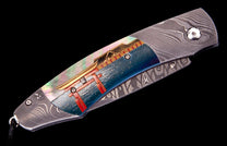 Damascus steel folding knife with iridescent mother-of-pearl inlay and a handle art depicting a red torii gate and golden temple roof.