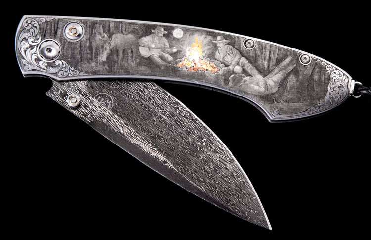 Engraved folding knife with Damascus steel blade, featuring a Western campfire scene of two men and a horse, partially open.