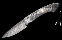 Engraved folding knife with a patterned Damascus blade and a handle depicting a Western campfire scene with a cowboy and horse, featuring ornate scrollwork and a decorative lanyard.