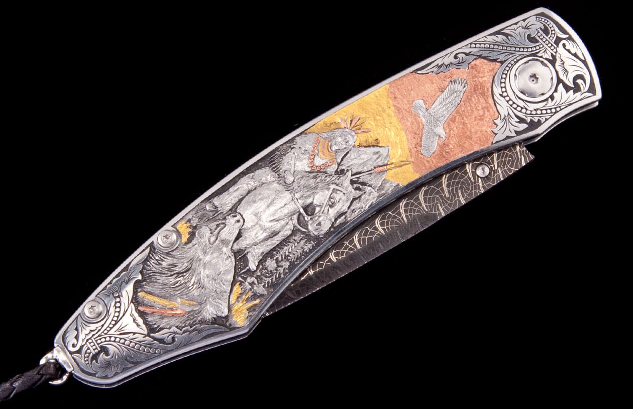 Engraved metal folding knife with a Native American on horseback, howling wolf, and flying eagle on gold and copper panels.