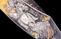 Western Frontier knife with intricate silver-toned engraving, featuring gold and copper accents of a rider and wolf, close-up.