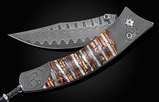Open folding knife with wavy Damascus steel blade and striped fossilized mammoth tooth handle, featuring decorative hardware and a braided leather lanyard.