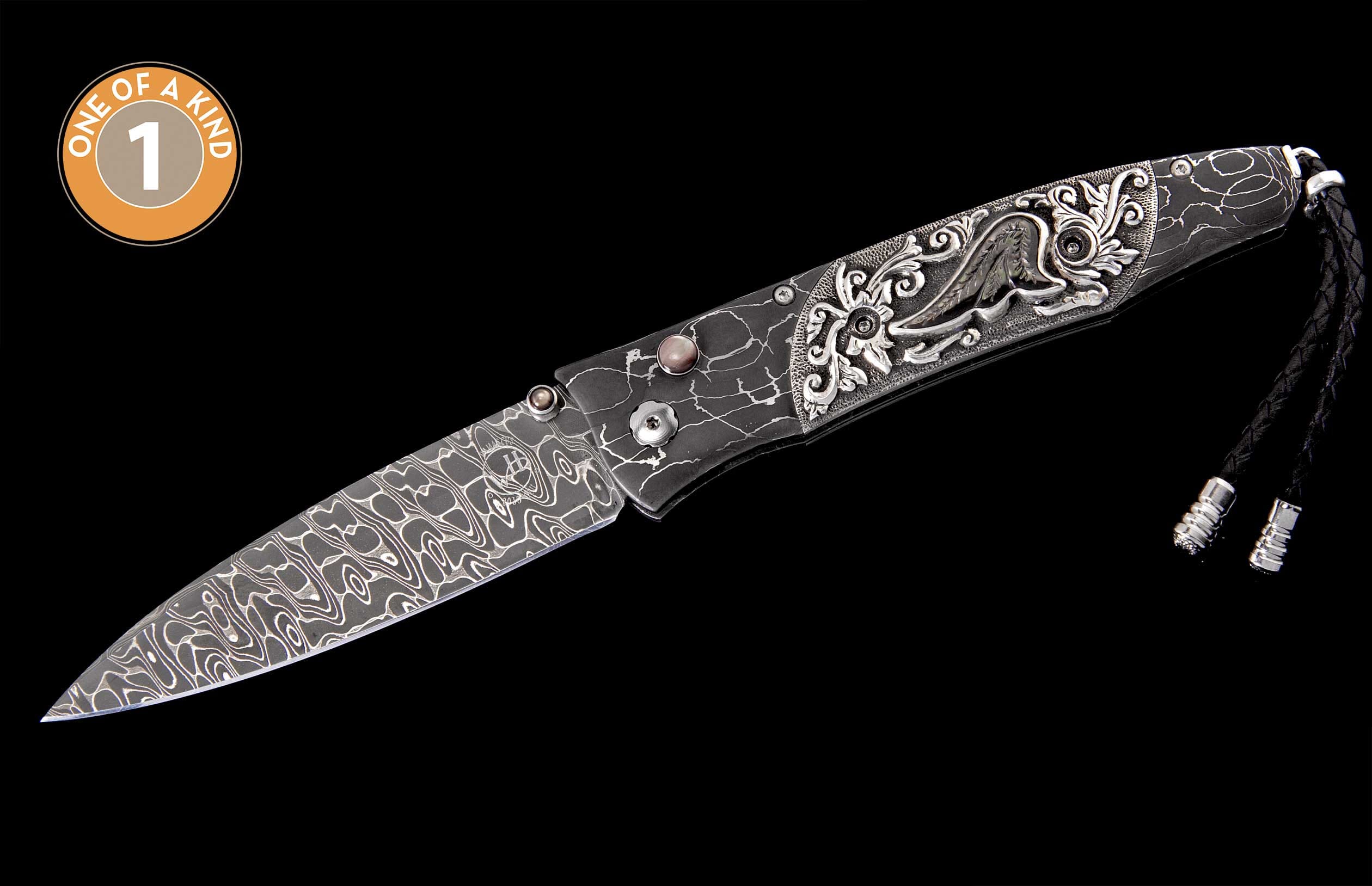 Ornate knife with a patterned Damascus steel blade, engraved silver handle accents, a dark gray cracked-pattern handle, and a black leather lanyard, marked 'ONE OF A KIND'.