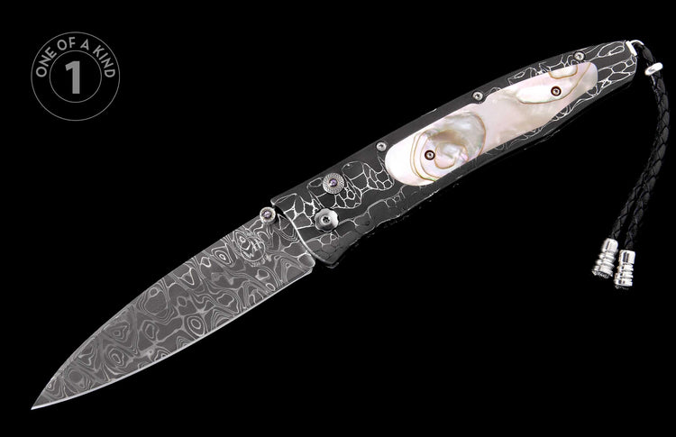 Damascus steel folding knife with a black handle, white organic patterns, iridescent mother-of-pearl inlays, and a black braided leather lanyard.