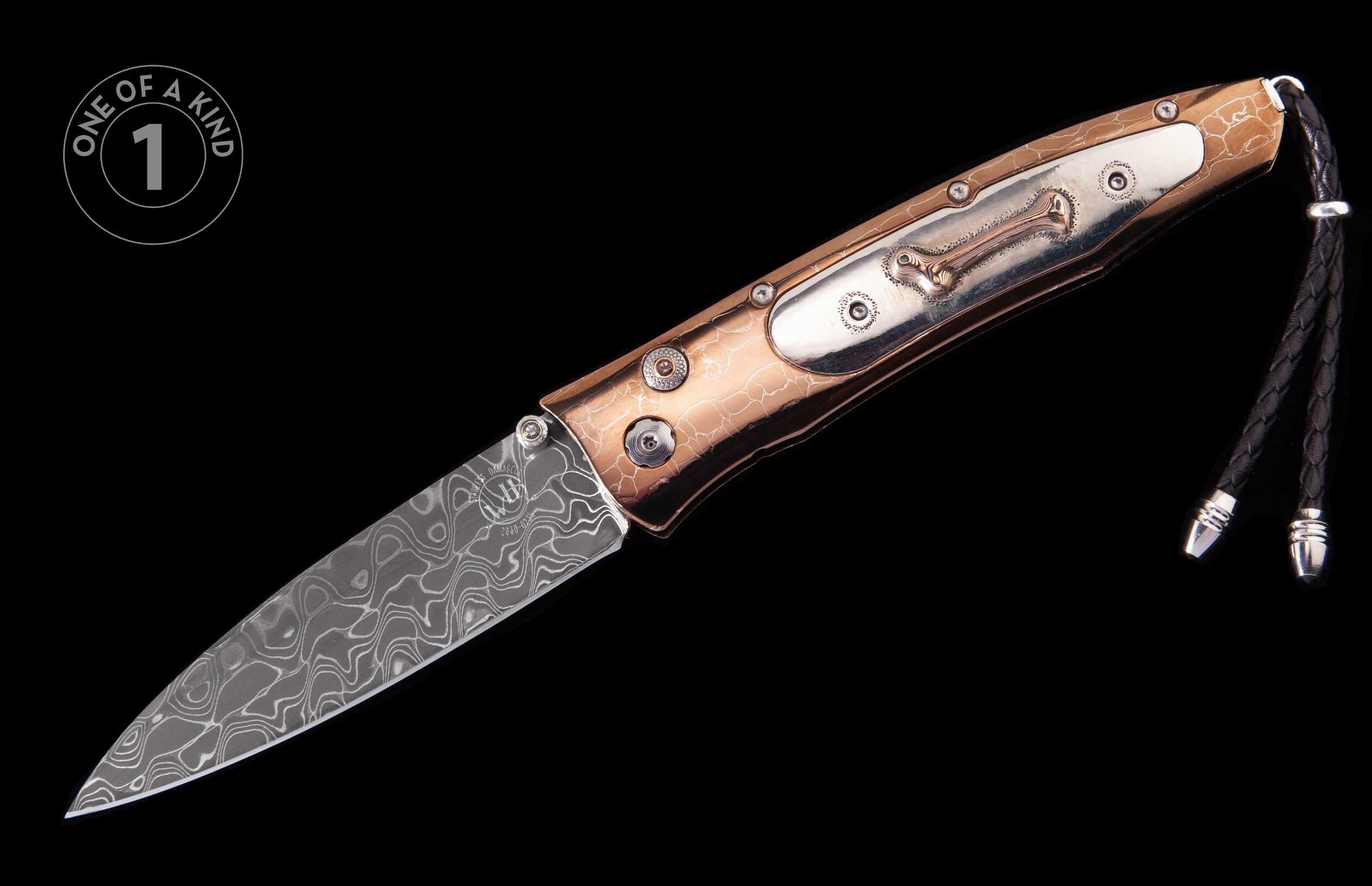 Folding knife with a wavy Damascus steel blade and a distressed copper handle with ornate silver inlays, finished with a black braided leather lanyard.