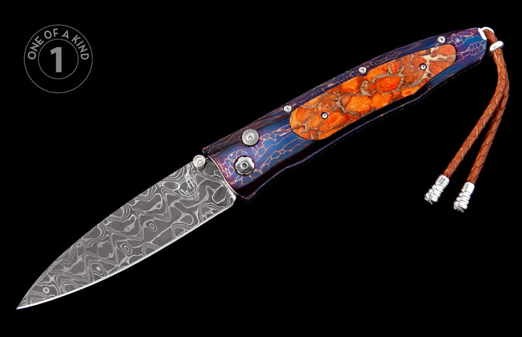 Folding knife with swirling Damascus blade, blue patterned handle with orange textured inlays, and a brown leather lanyard.