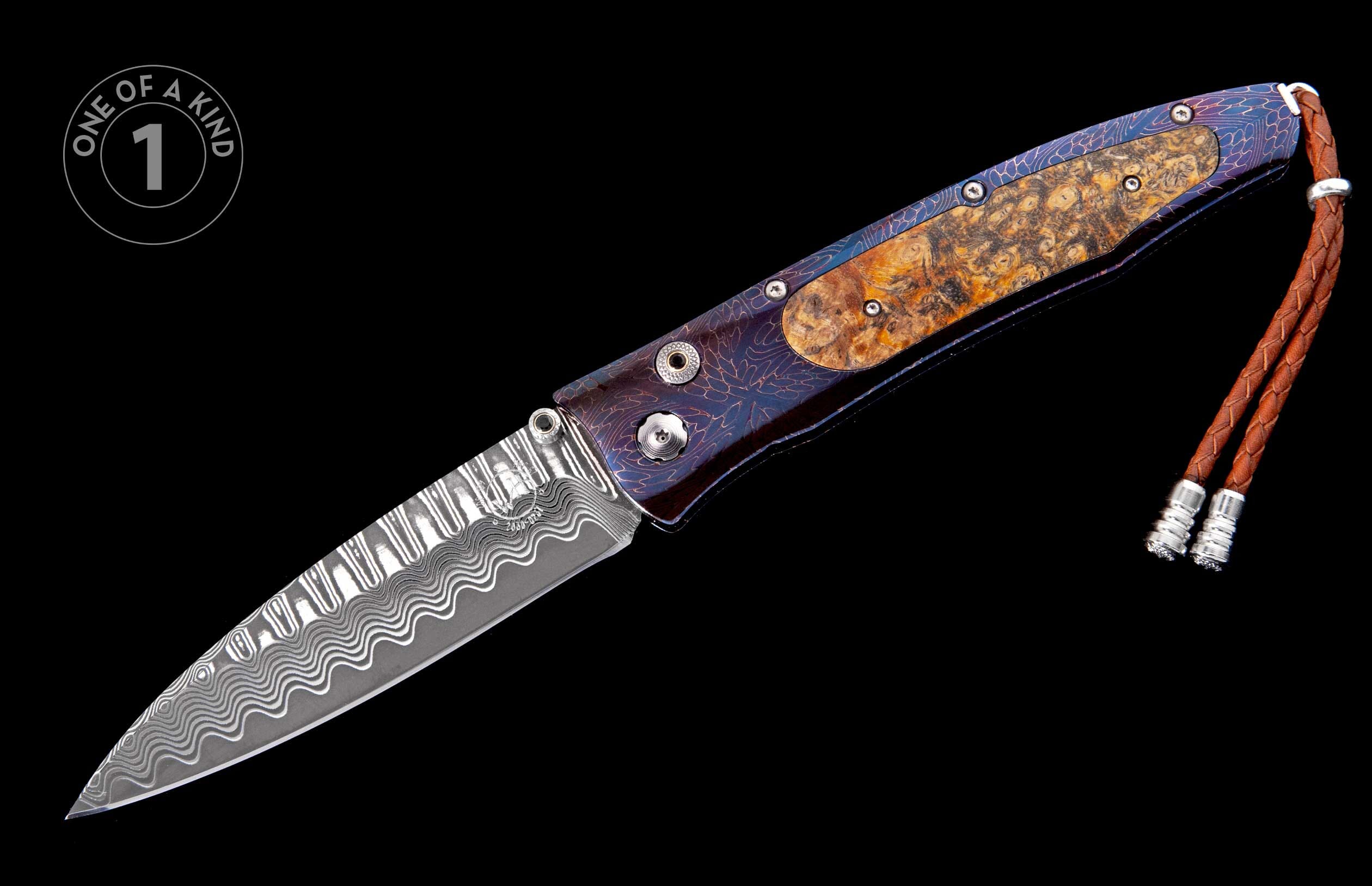 Damascus steel folding knife with a patterned handle, burl wood inlay, and a braided leather lanyard.