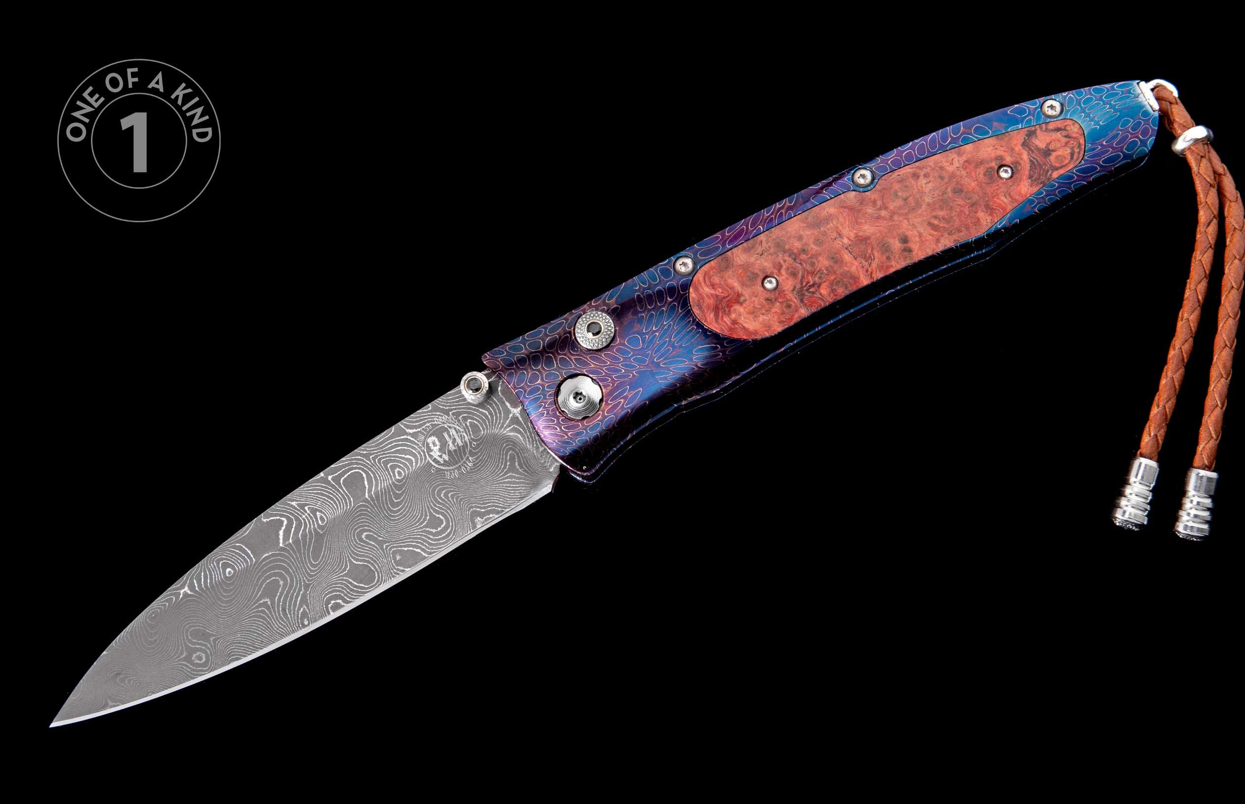 Folding knife with a Damascus blade, burl wood handle, blue and purple patterned metal, a brown braided leather lanyard, and a 'one of a kind' badge.