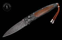 Folding knife with a patterned Damascus steel blade, dark etched frame, brown wood handle, and braided leather lanyard.
