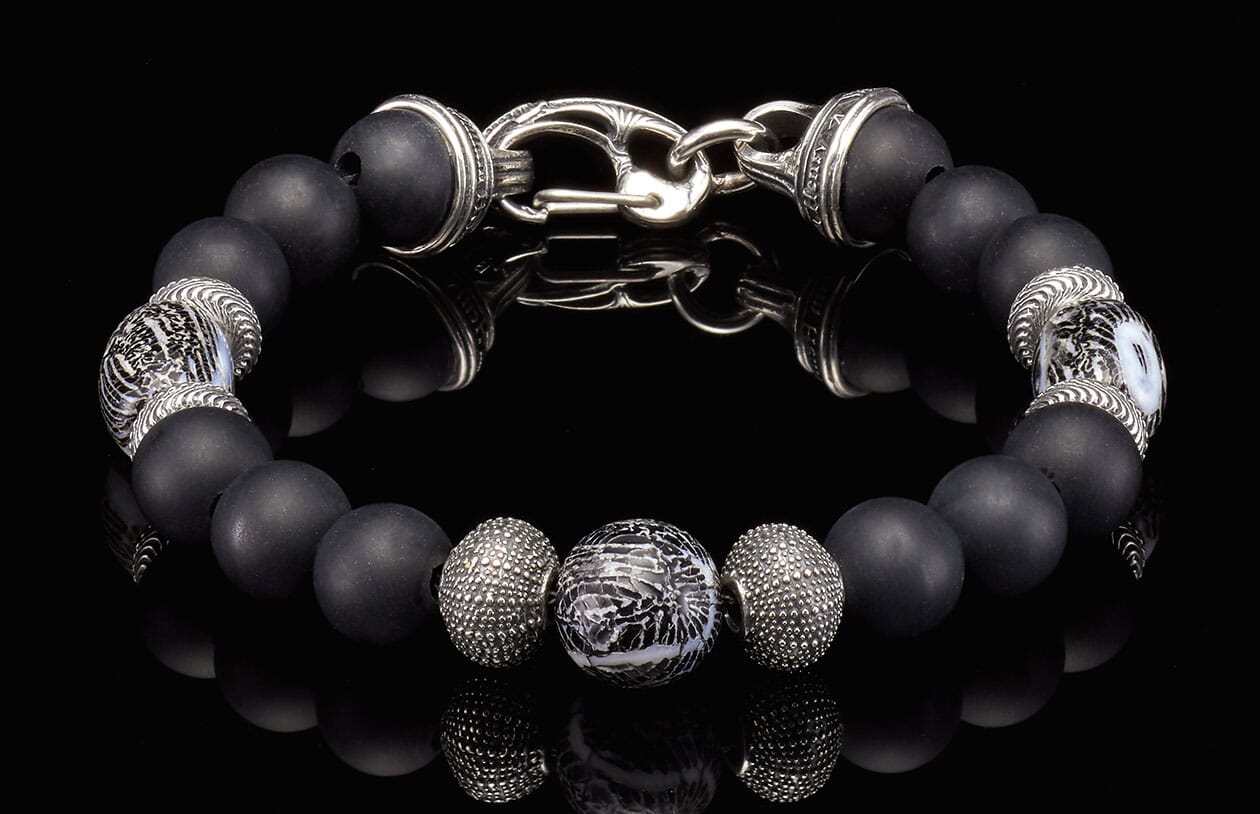 Black beaded bracelet with matte onyx beads, ornate silver accents, and a distinctive patterned centerpiece bead.