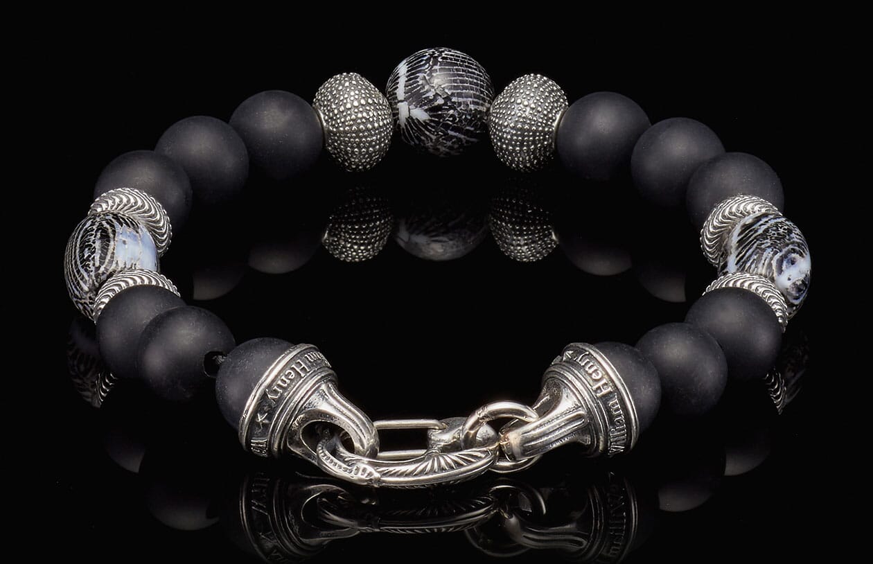 Black matte bead bracelet by William Henry, featuring ornate sterling silver spacers, a patterned bead, and an engraved clasp.