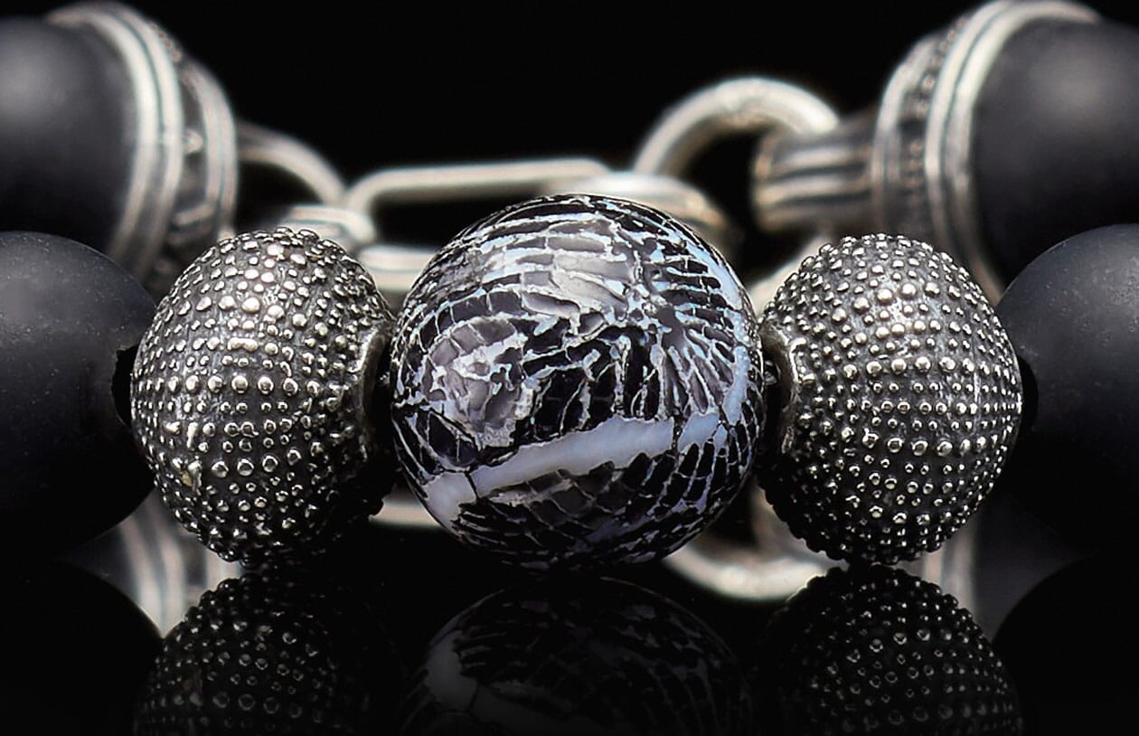 Beaded bracelet with a cracked black and white central bead, textured silver, and matte black beads.
