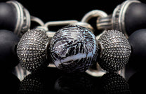 Beaded bracelet with a cracked black and white central bead, textured silver, and matte black beads.