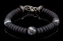 Matte black beaded bracelet with a silver hook clasp and three patterned white and black glass accent beads.