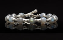 Silver and labradorite beaded bracelet with a toggle clasp on a reflective black surface.