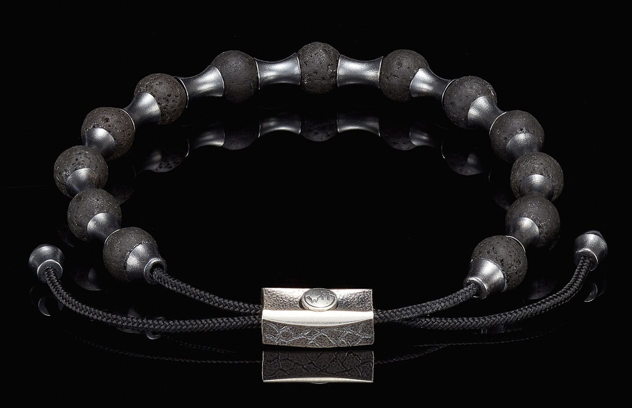 Black lava stone beaded bracelet with silver-tone spacers, a textured silver clasp, and adjustable black cord.