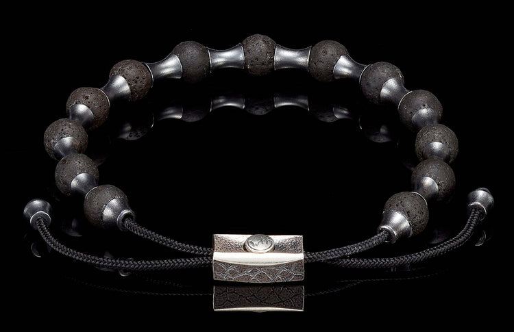 Black lava stone beaded bracelet with silver-tone spacers, a textured silver clasp, and adjustable black cord.