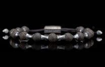 Dark lava stone and silver metal beaded bracelet featuring porous beads and reflective spacers on a black surface.