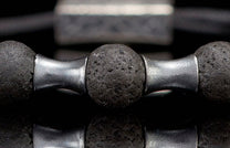 Close-up of a dark grey lava stone bracelet with textured beads and shiny silver metal separators.