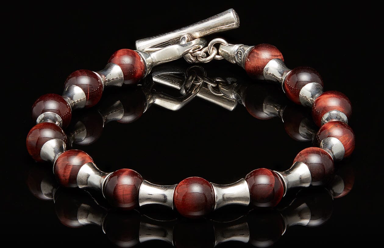 Deep red beaded bracelet with silver-toned metal spacers, a toggle clasp, and subtle striations on the beads.