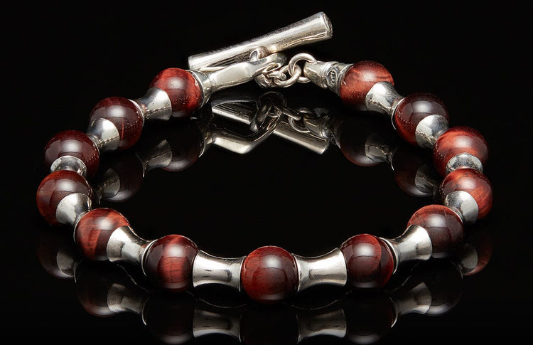 Deep red beaded bracelet with silver-toned metal spacers, a toggle clasp, and subtle striations on the beads.