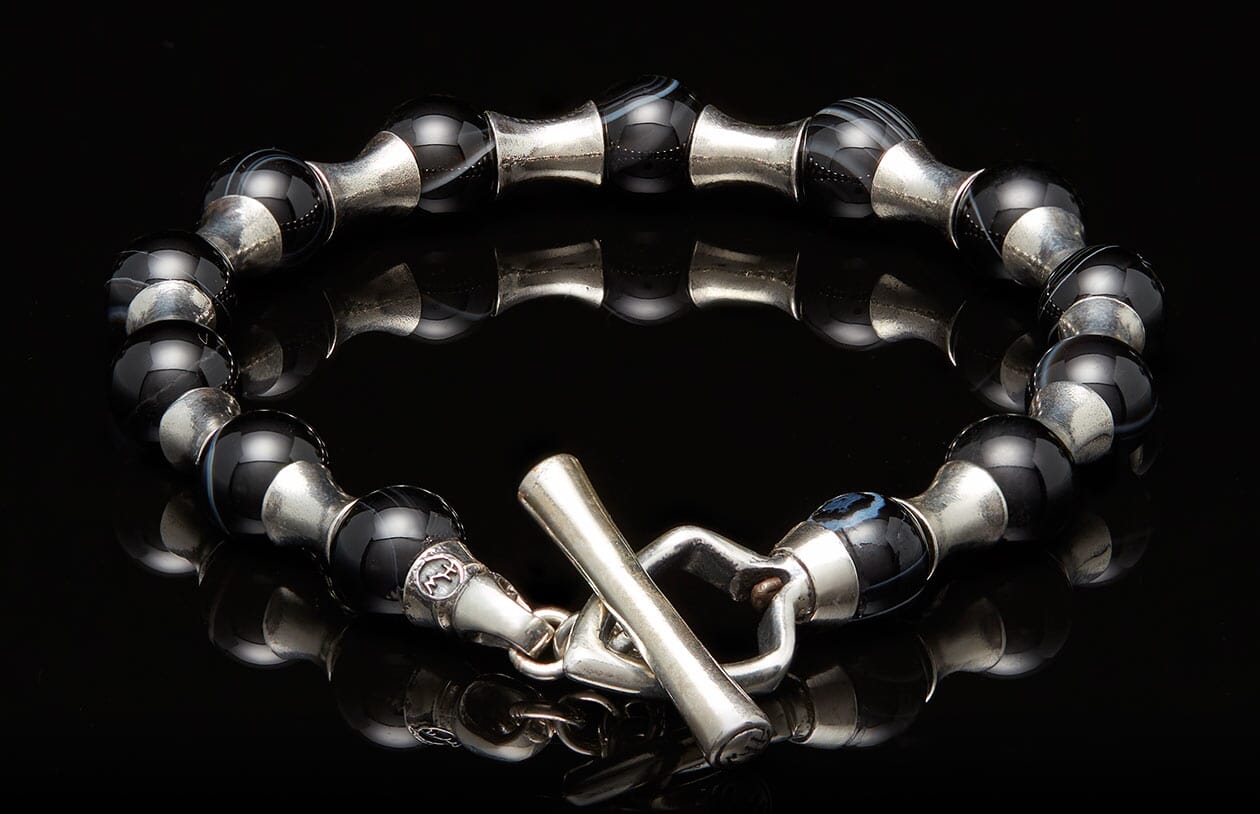 Black agate bead bracelet with silver barrel separators and a decorative animal head toggle clasp.