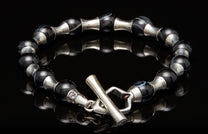 Black agate bead bracelet with silver barrel separators and a decorative animal head toggle clasp.