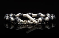 Black and silver beaded bracelet featuring polished black and white striped agate beads and a silver toggle clasp on a reflective surface.