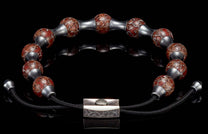 Bracelet with reddish-brown crackled beads, matte silver spacers, and a textured rectangular clasp on a reflective surface.