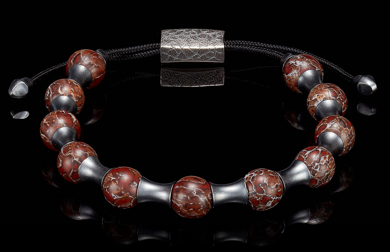 Reddish-brown patterned bead bracelet with dark silver metal spacers, a textured rectangular clasp, and black adjustable cord.