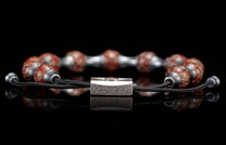 BB19 DB RB - REG ADJ|Bracelet with mottled red-brown stone beads, silver metal spacers, and a textured rectangular clasp on black cord, reflected.