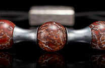 BB19 DB RB - REG ADJ|Reddish-brown patterned beaded bracelet with matte silver cylindrical spacers, reflecting on a dark surface.