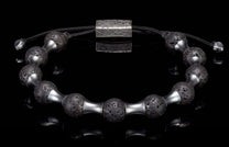 Black lava stone and silver-tone metal beaded bracelet with a textured rectangular clasp, reflected on black.