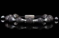 Black lava stone bracelet with silver metal barbell-shaped spacers, featuring porous texture and a reflective surface.