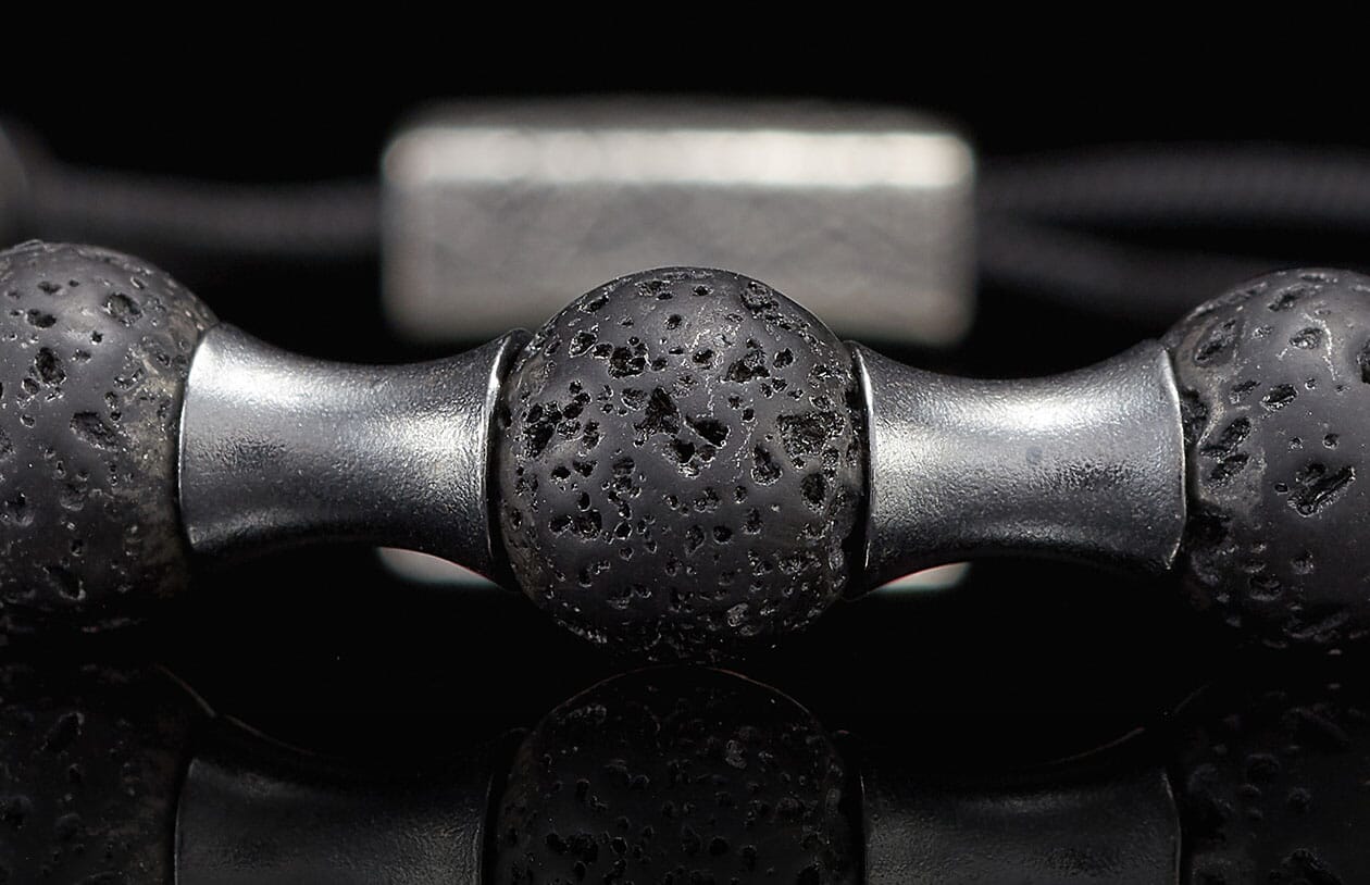 Dark lava stone beaded bracelet with silver-toned metal spacers, close-up.