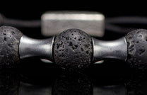 Dark lava stone beaded bracelet with silver-toned metal spacers, close-up.