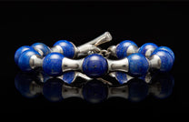Lapis lazuli and silver beaded bracelet with a toggle clasp on a reflective black surface.