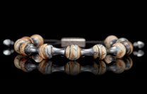 Mammoth Zenith bracelet with striped beige, black, and grey stone beads and dark metal spacers on a reflective surface.