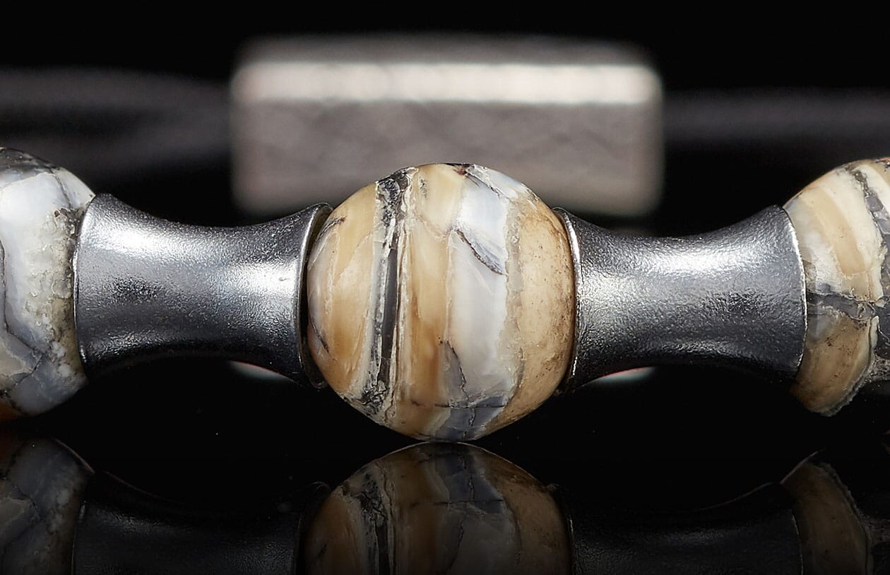 Jewelry bead crafted from naturally patterned mammoth tusk, flanked by textured silver metal spacers.