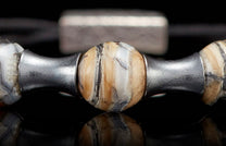 Jewelry bead crafted from naturally patterned mammoth tusk, flanked by textured silver metal spacers.