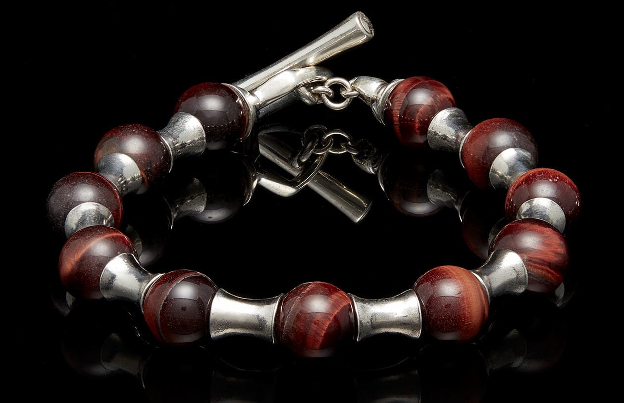 Beaded bracelet with deep red tiger's eye beads and polished silver spacers, featuring a toggle clasp.