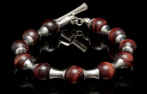 Beaded bracelet with deep red tiger's eye beads and polished silver spacers, featuring a toggle clasp.